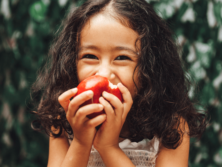 A young girl biting an apple with a big smile ?? 
